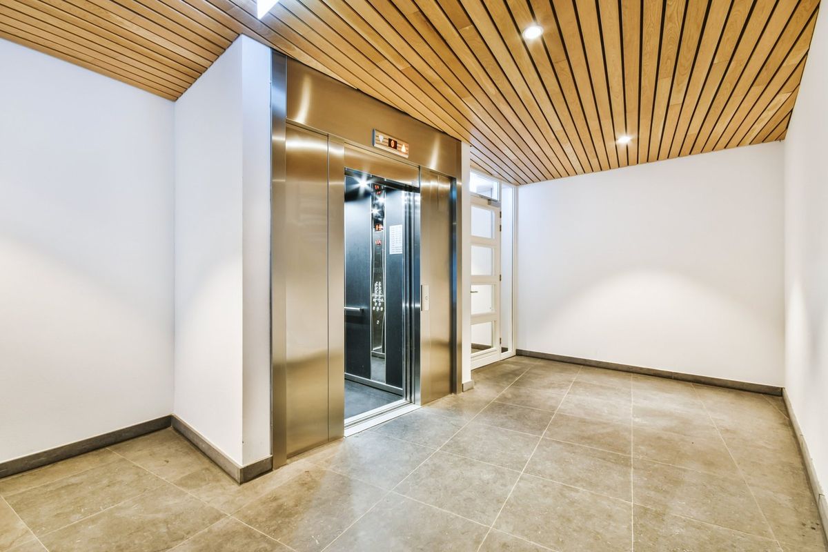 Bright apartment building lobby with recessed ceiling lights at the elevator