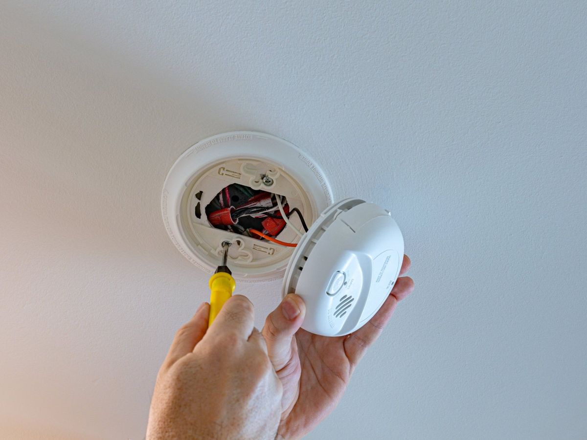 Hardwired smoke alarm being connected to its ceiling mounting plate
